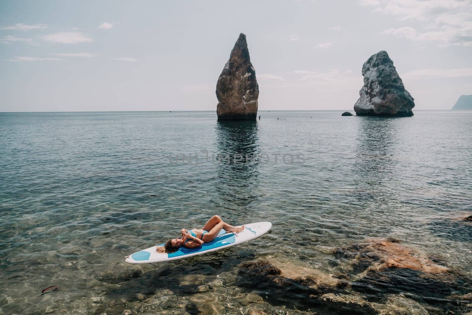 Woman sup yoga. Happy sporty woman practising yoga pilates on paddle sup surfboard. Female stretching doing workout on sea water. Modern individual female hipster outdoor summer sport activity. by panophotograph