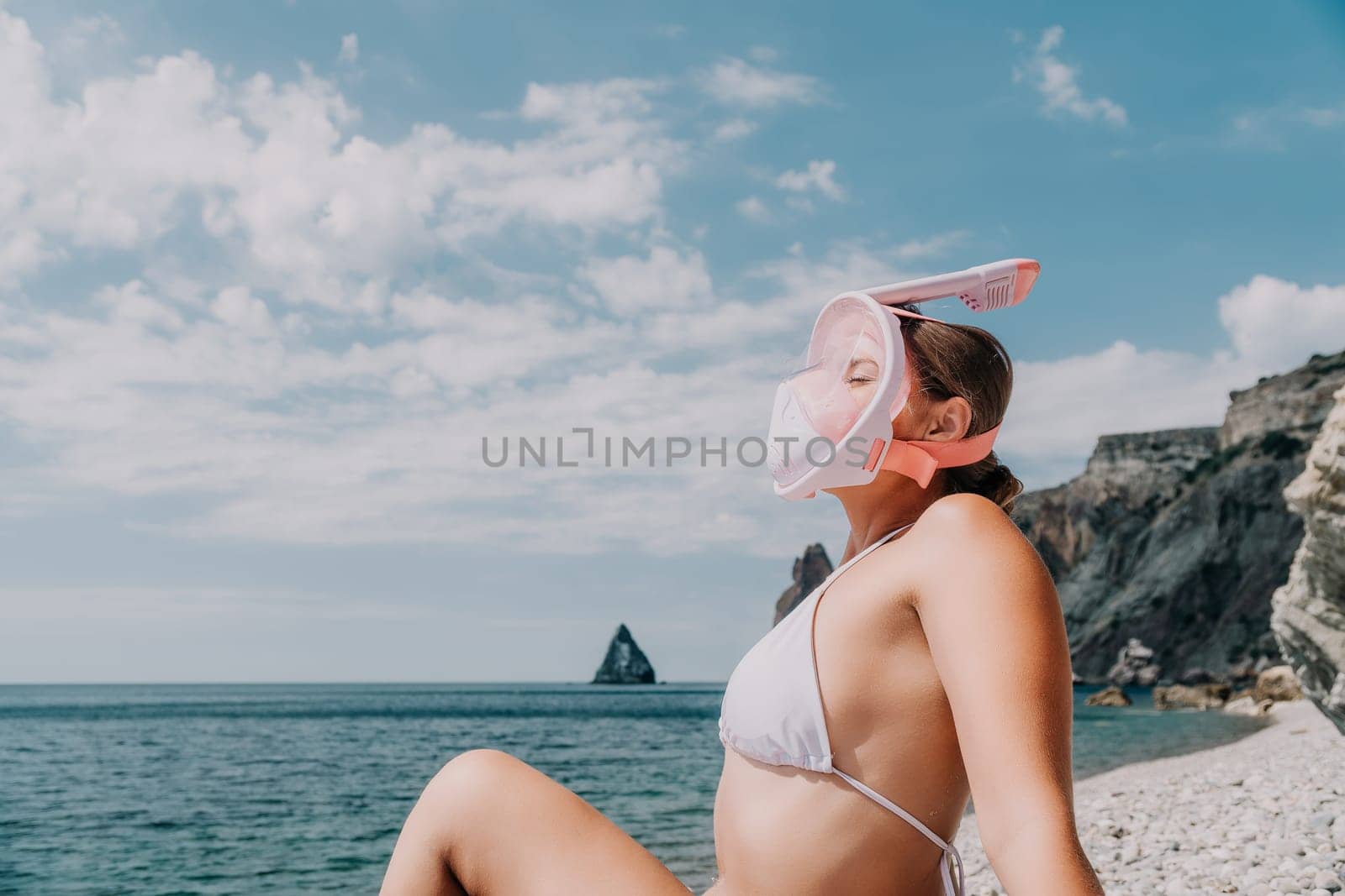 Young happy woman in white bikini put pink snorkeling mask on beach before swimming. girl having fun relaxing on beautiful beach. Beach lifestyle