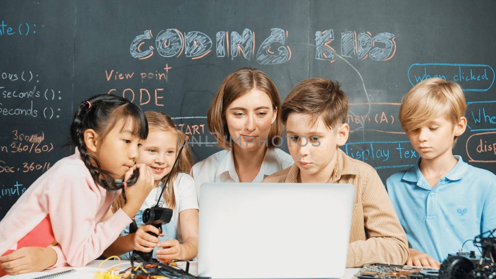 Diverse student writing engineering code while boy fixing mother board. Teacher giving advice and teaching about robotic system while learner studying and learning about coding prompt. Erudition.