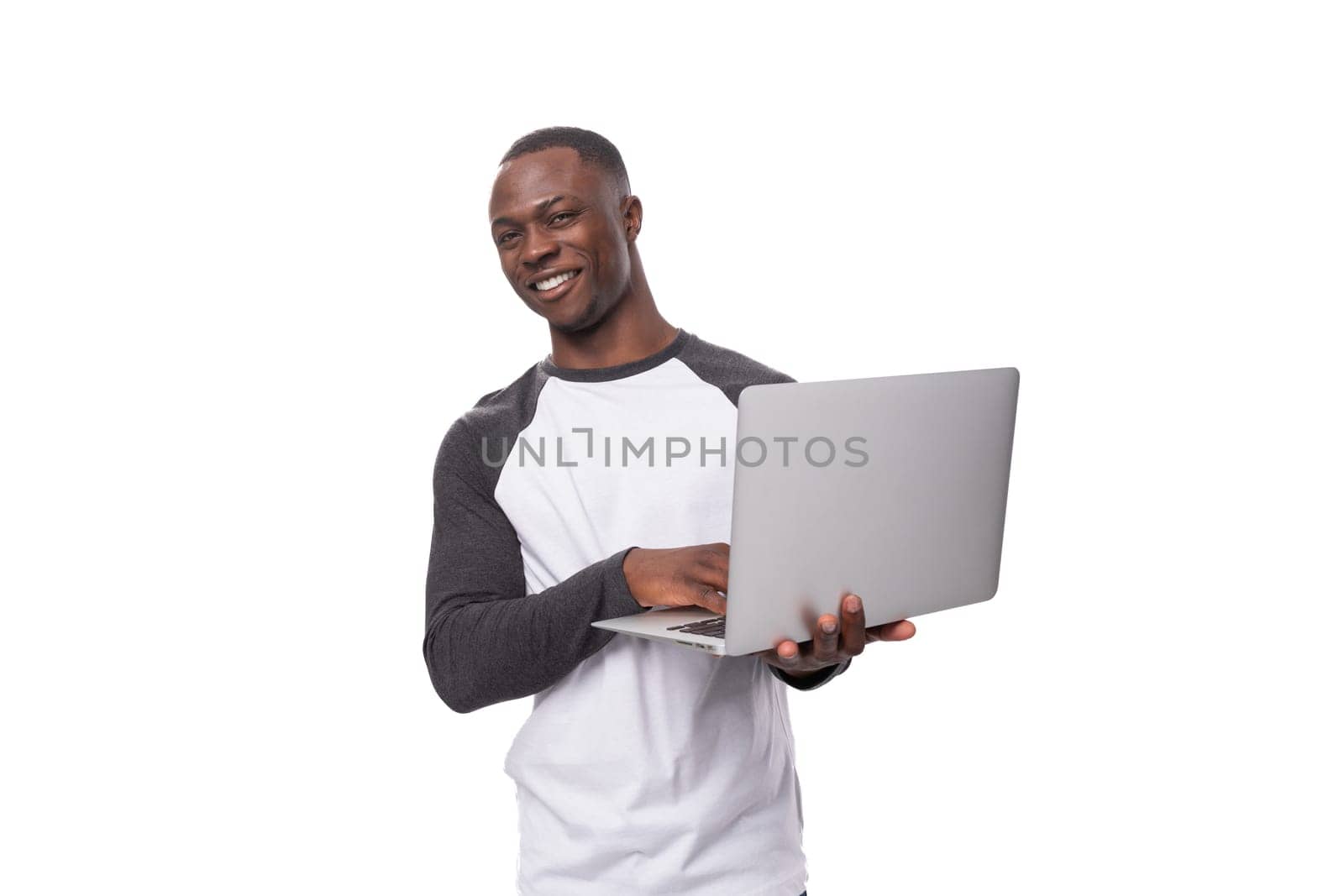 a young American guy dressed in a long-sleeved sweater holds a laptop for work in his hands.