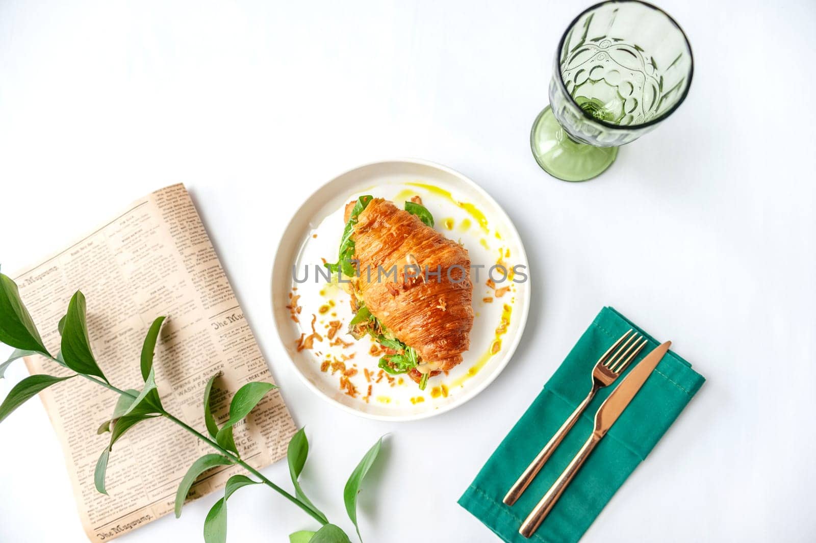 Croissant sandwich with ham, cheese and vegetables in white plate. Top view with copy space on white table