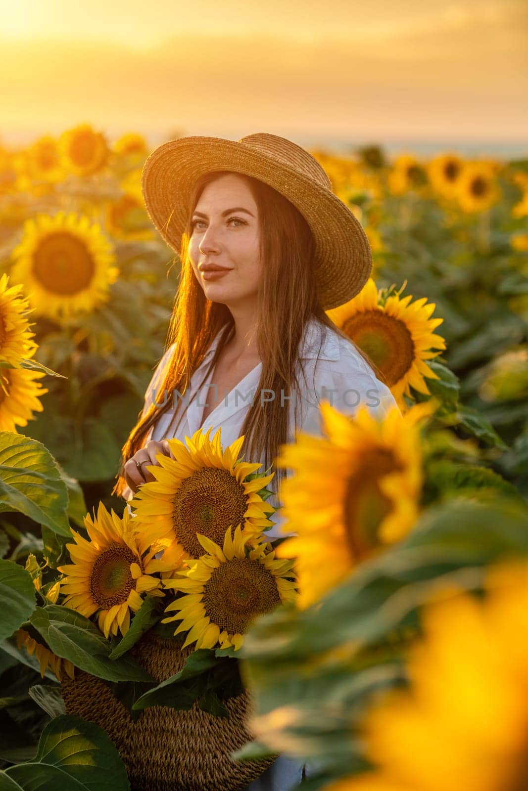 A girl in a hat on a beautiful field of sunflowers against the s by Matiunina