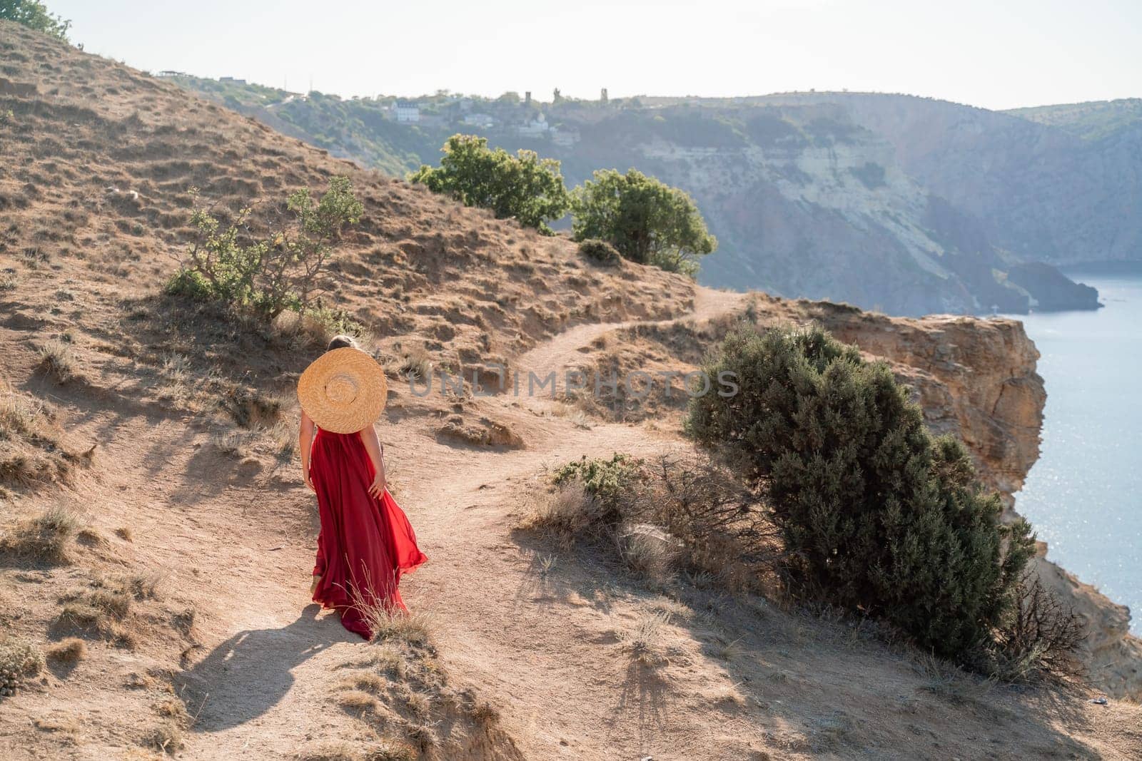 A woman in a red flying dress fluttering in the wind, against the backdrop of the sea. by Matiunina