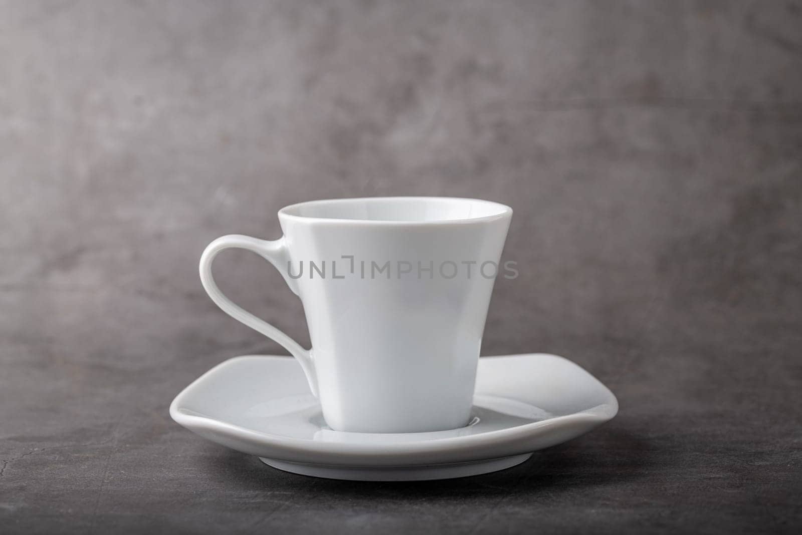 Empty white porcelain cup on gray stone background by Sonat