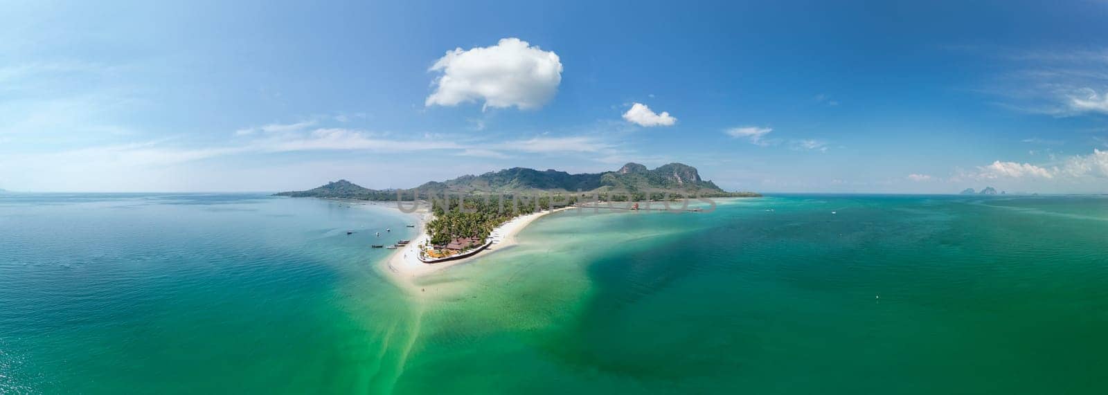 Drone aerial view at Koh Muk a tropical island with palm trees and soft white sand, and a turqouse colored ocean in Koh Mook Trang Thailand, panorama view of Koh Mook on a sunny day