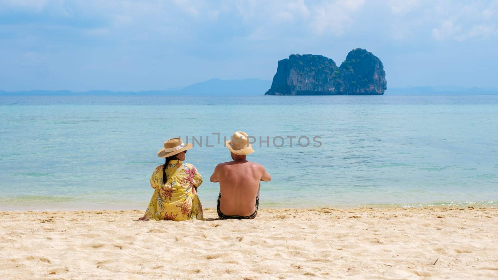 a couple of men and woman sitting on the tropical beach at Koh Ngai island, the backside of a couple lying down on the beach