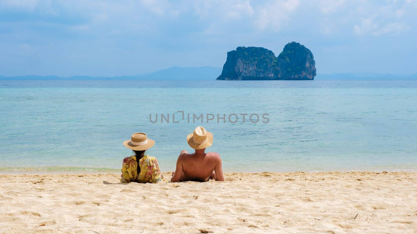 a couple of men and woman sitting on the tropical beach at Koh Ngai island by fokkebok