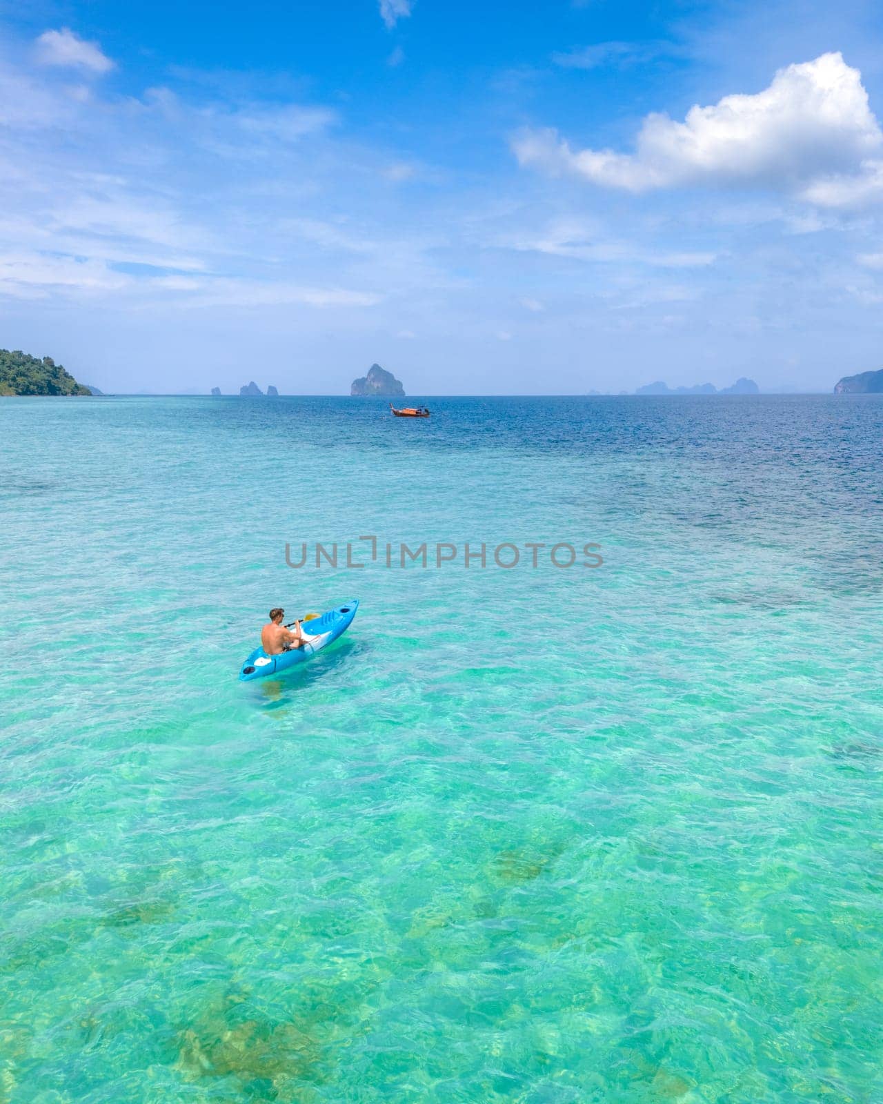 Young men in a kayak at the bleu turqouse colored ocean of Koh Kradan a tropical island with a coral reef in the ocean, Koh Kradan Trang Thailand on a sunny day with a blue sky