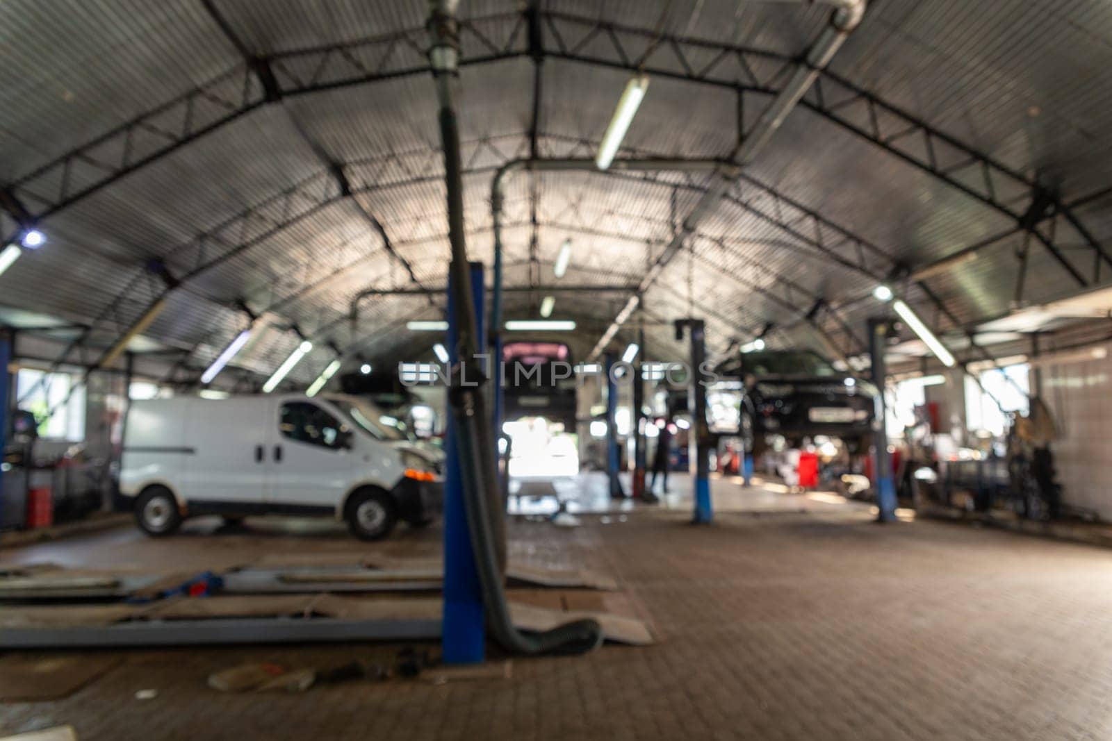 Blurred background image with cars in automobile repair service center. Modern car repair station with a large number of lifts and specialized equipment for diagnostics and service repair car