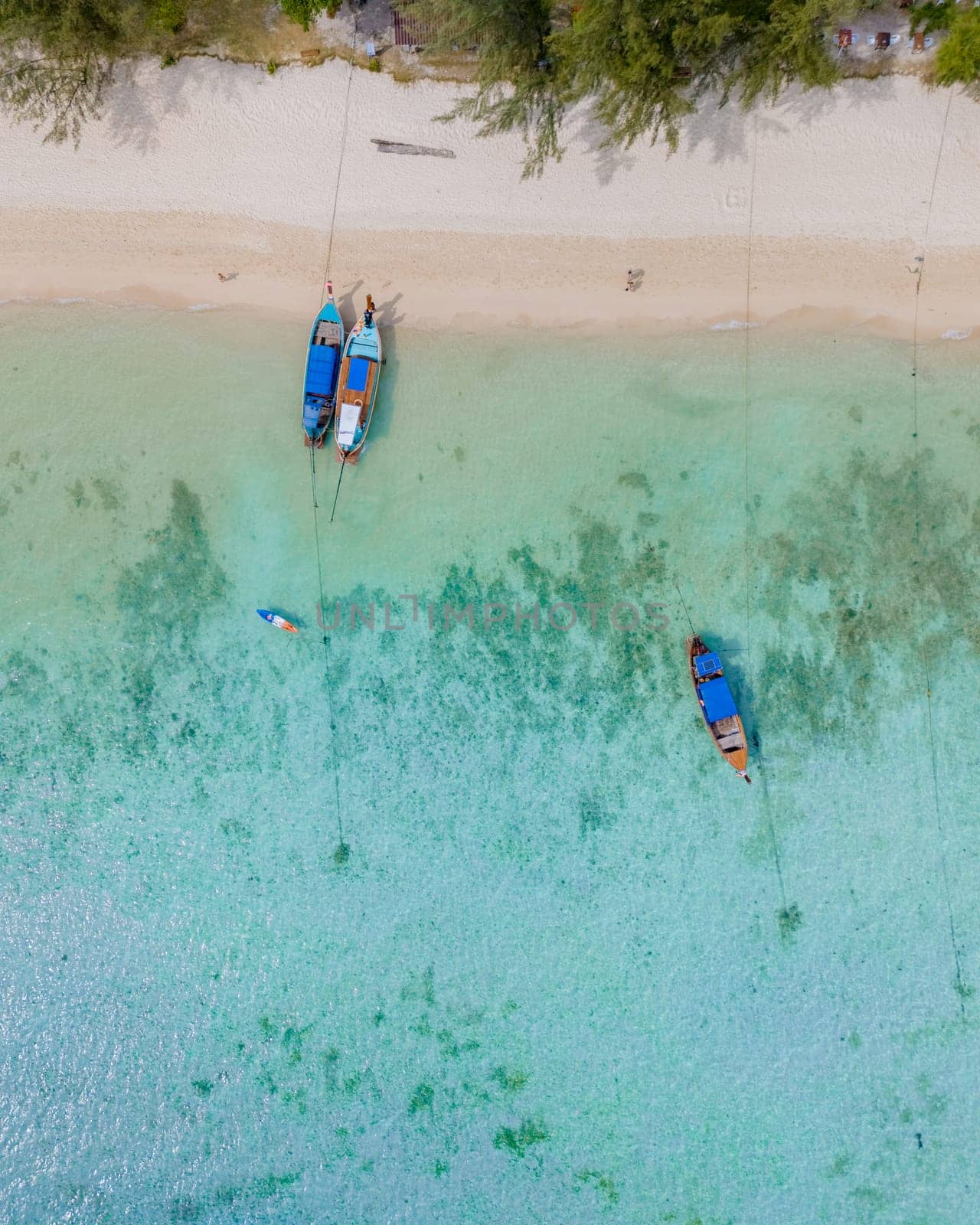 Top view at longtail boats in a blue ocean at the beach of Koh Ngai island Thailand, white sand, and a turqouse colored ocean in Koh Ngai Trang Thailand