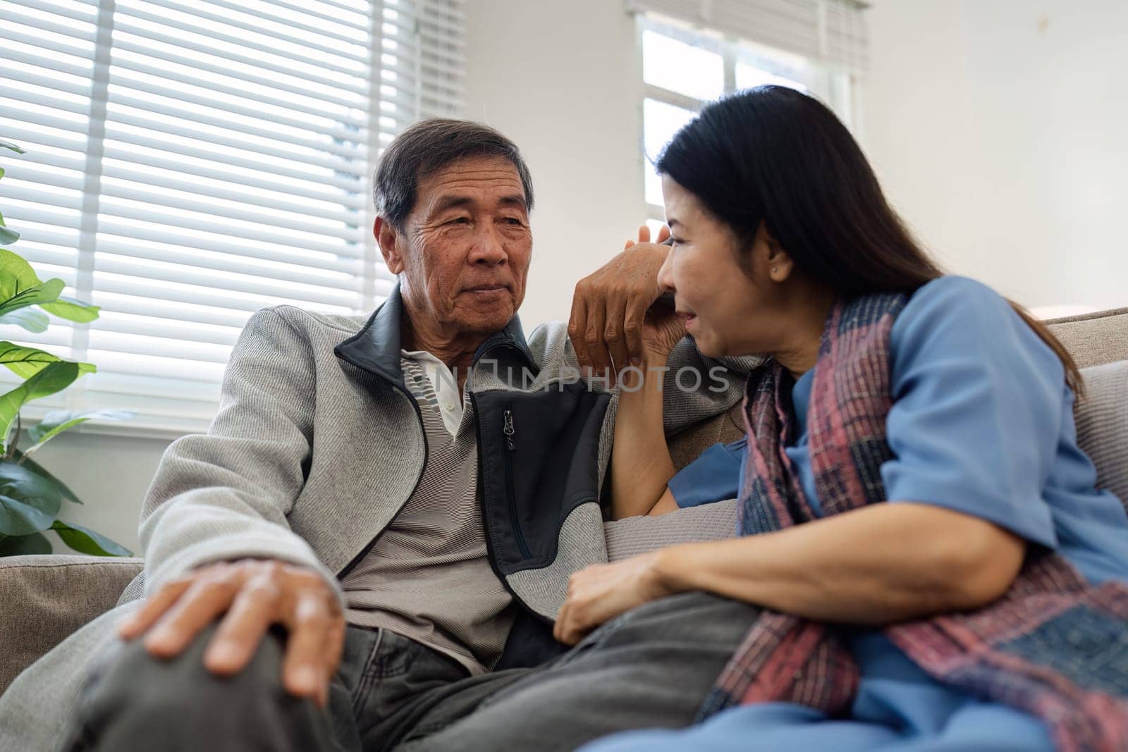 Older couples sit and chat and head over each other relaxed and happy on sofa at home on weekday in comfortable by itchaznong
