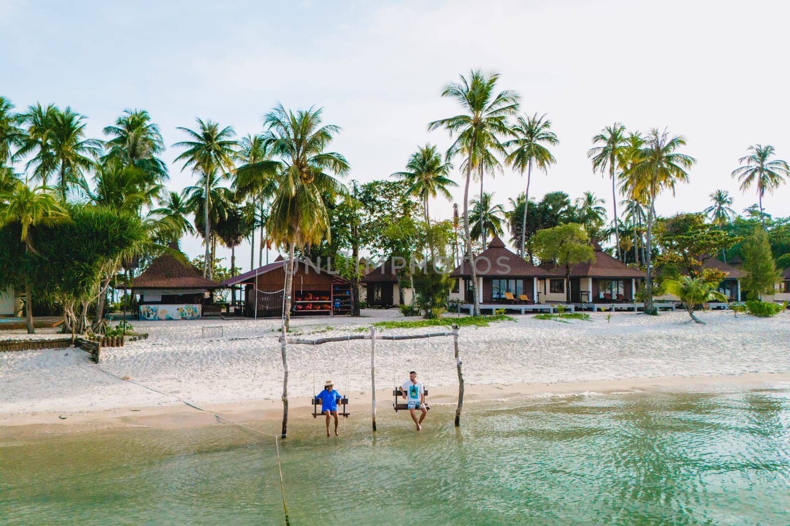 a couple of men and woman on a swing at the beach of Koh Muk Thailand by fokkebok