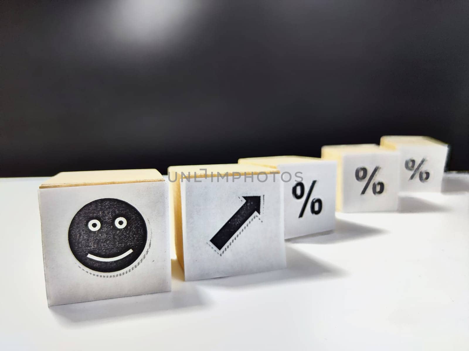 Wooden cubes in a column and row with white signs with a smiley sign, an arrow, a percentage. The concept of positivism. Positive thinking leads to the achievement of results and profits