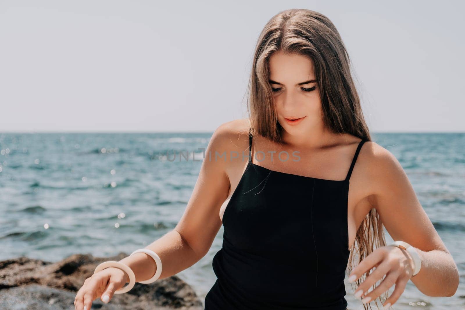 Woman travel sea. Young Happy woman in a long red dress posing on a beach near the sea on background of volcanic rocks, like in Iceland, sharing travel adventure journey