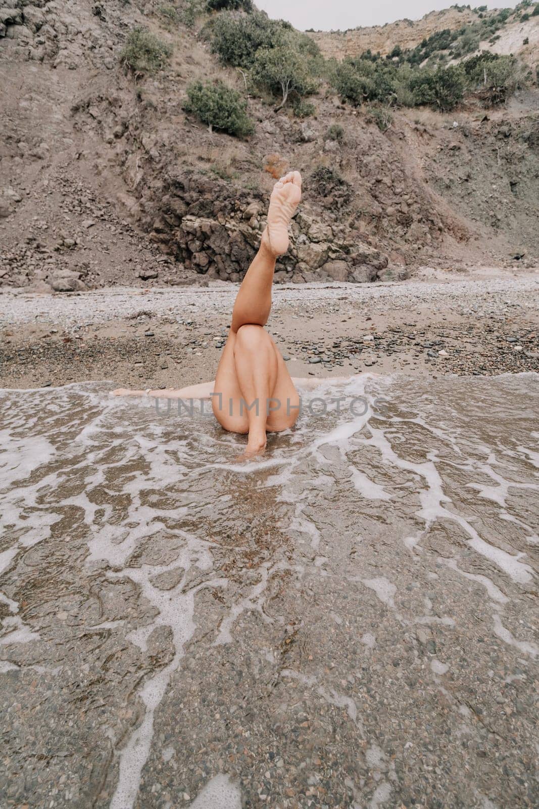 Woman travel sea. Young Happy woman in a long red dress posing on a beach near the sea on background of volcanic rocks, like in Iceland, sharing travel adventure journey