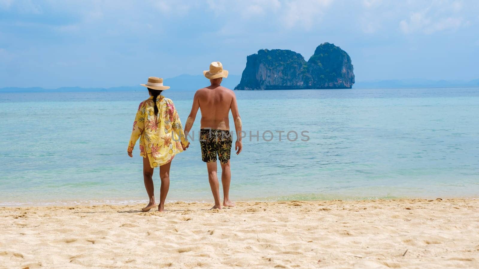 a couple of Thai women and European men on the beach of the tropical Island Koh Ngai island Thailand, with soft white sand, and a turqouse colored ocean in Koh Ngai Trang Thailand