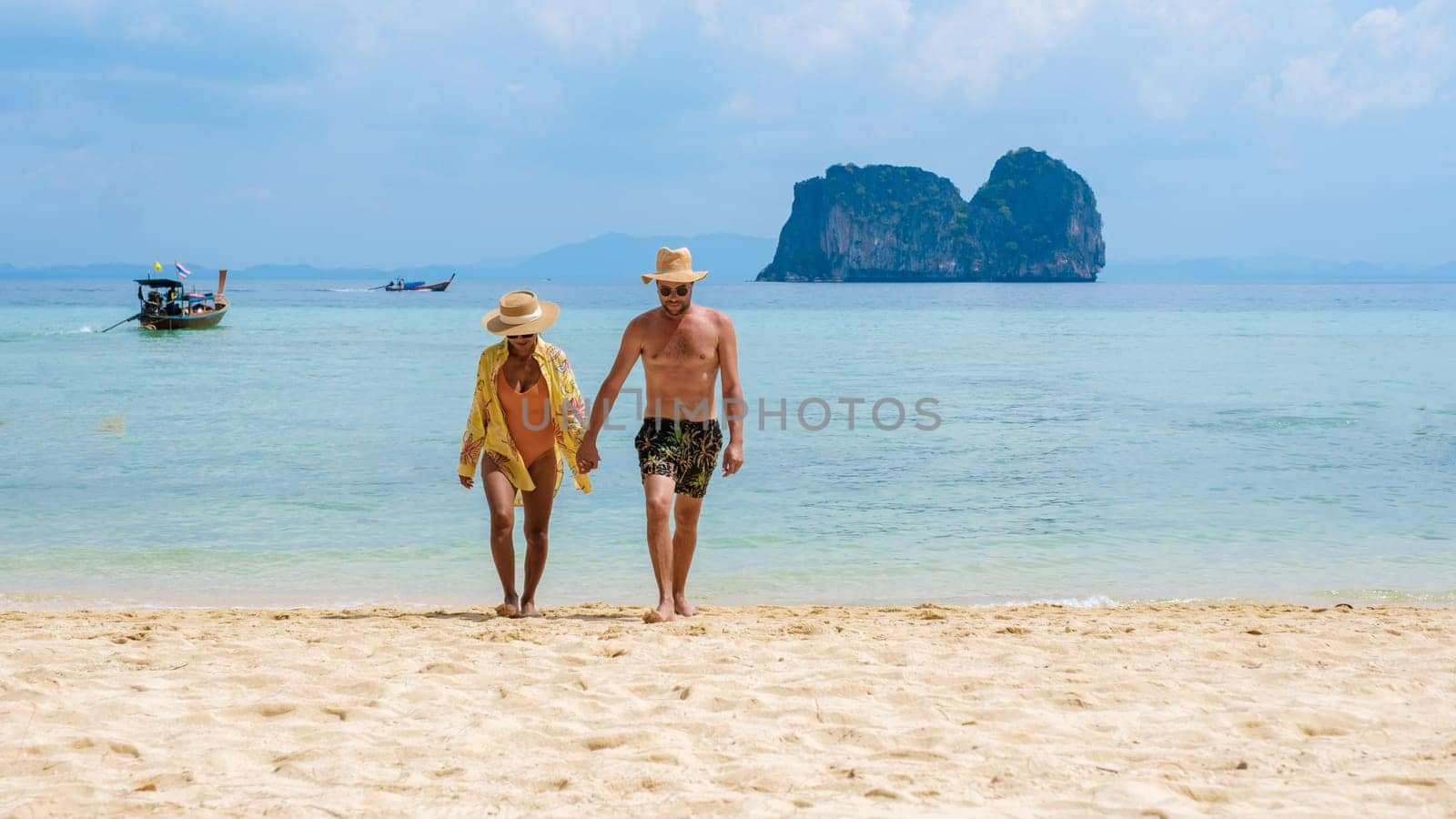 a couple of Thai women and European men on the beach of the tropical Island Koh Ngai island Thailand, with soft white sand, and a turqouse colored ocean in Koh Ngai Trang Thailand
