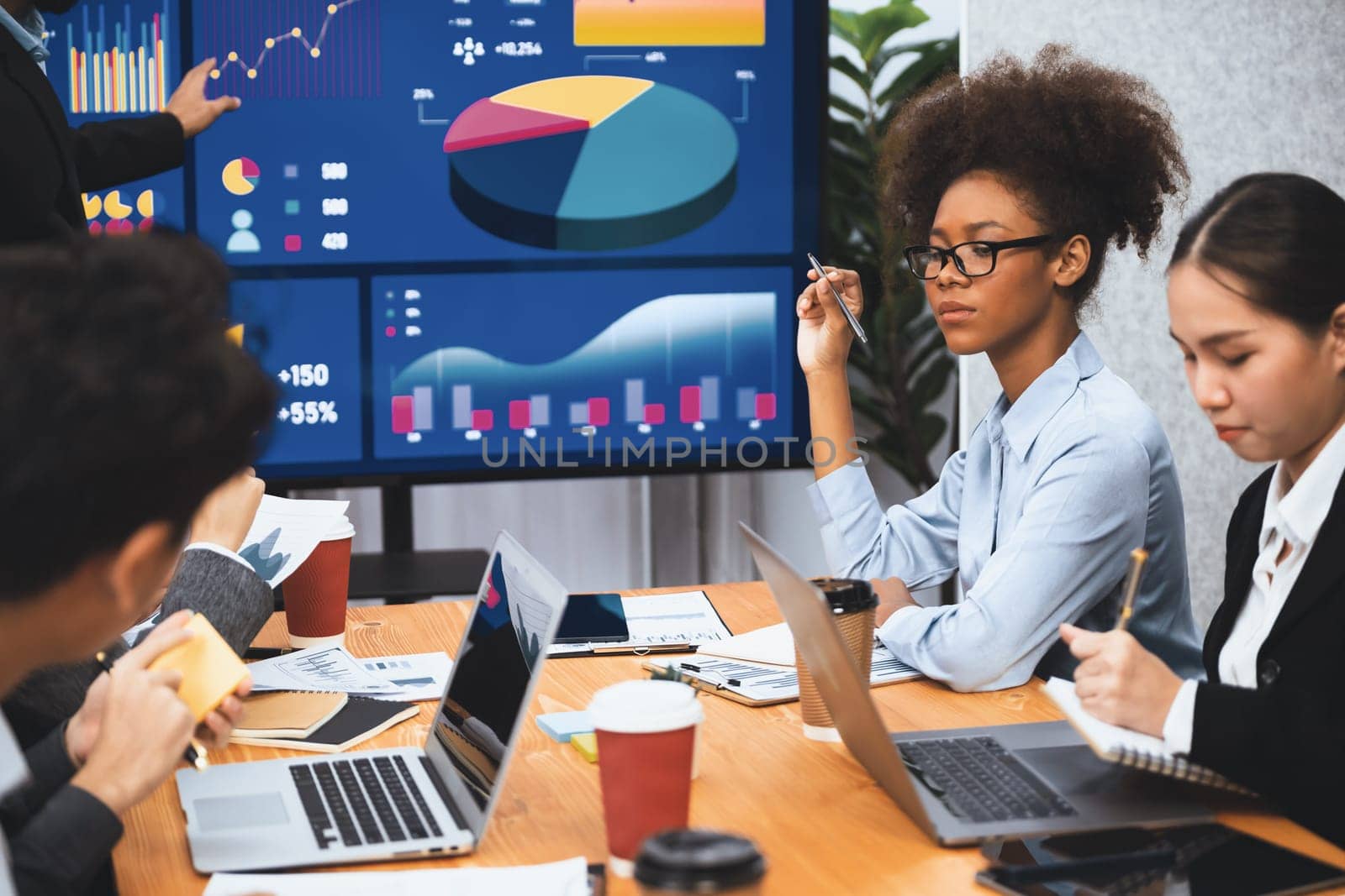 Multiracial analyst team use BI dashboard data to analyze financial report on meeting table. Group of diverse business people utilize data analysis by FIntech for business marketing decision. Concord