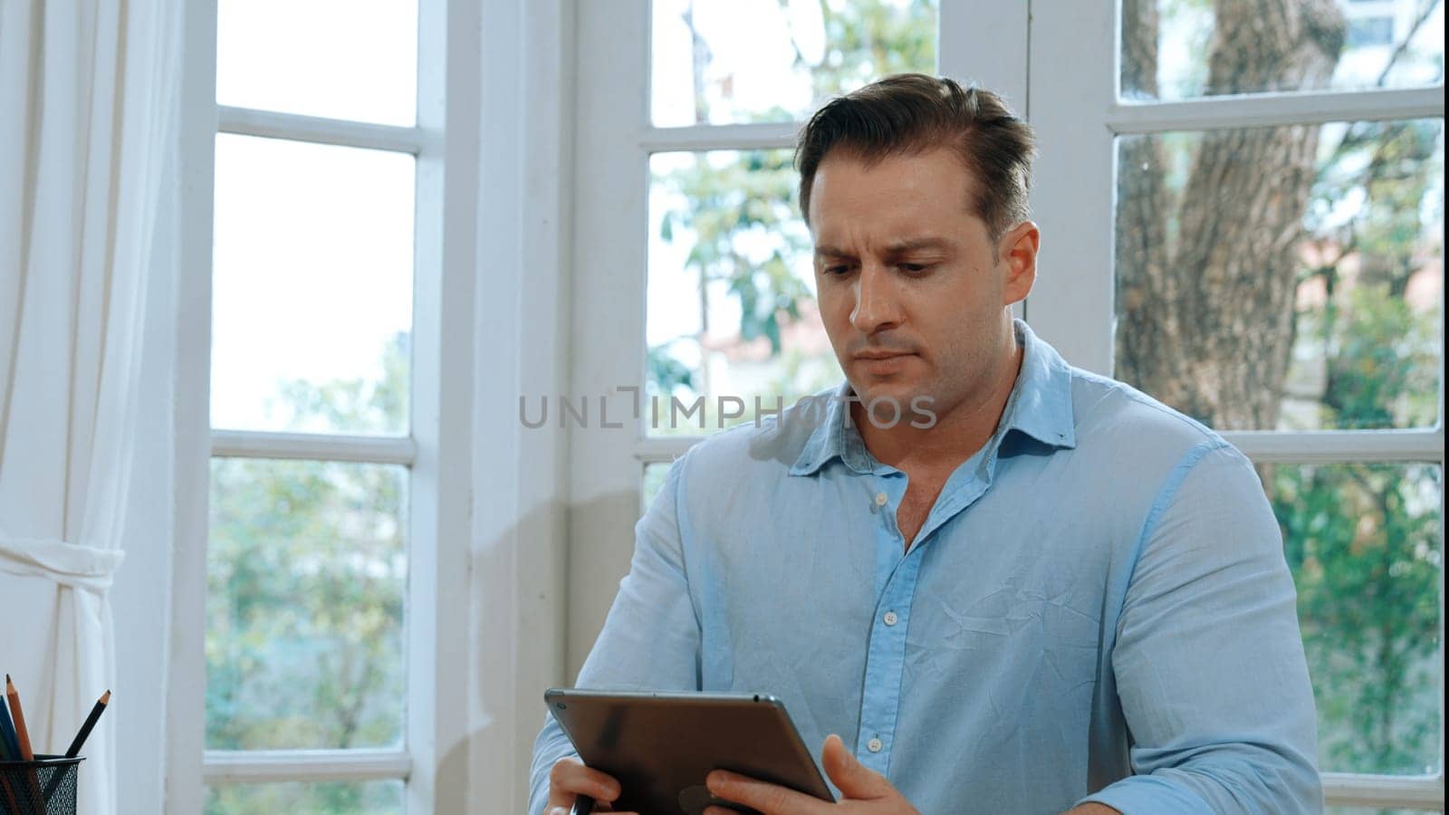 Businessman struggle to solve work problem from home using laptop, sitting on his desk at home office with stressed and frustrated expression, trying to figure out solution for problem. Synchronos