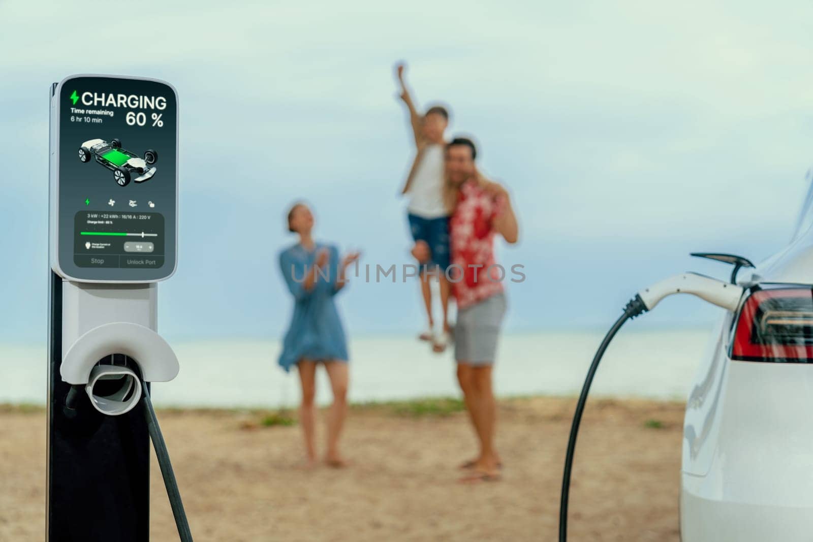 EV car charging with blurred cheerful family on the beach. Perpetual by biancoblue