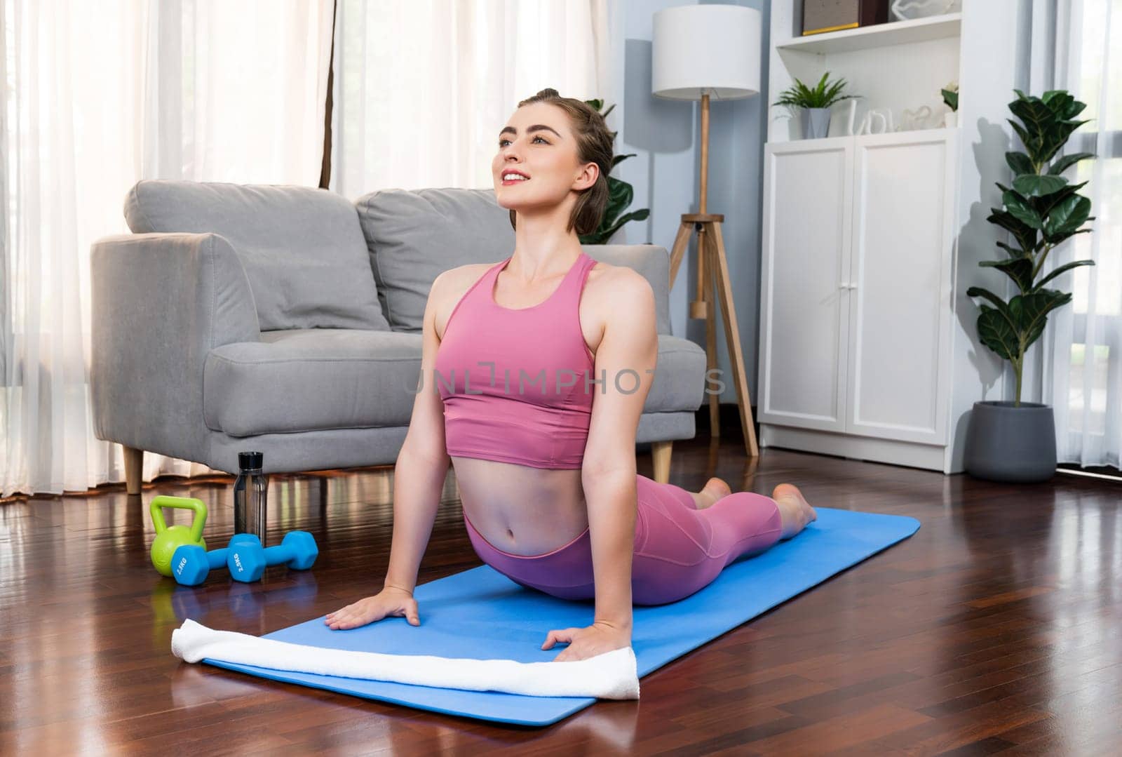 Flexible and dexterity woman in sportswear doing yoga position in meditation posture on exercising mat at home. Healthy gaiety home yoga lifestyle with peaceful mind and serenity.