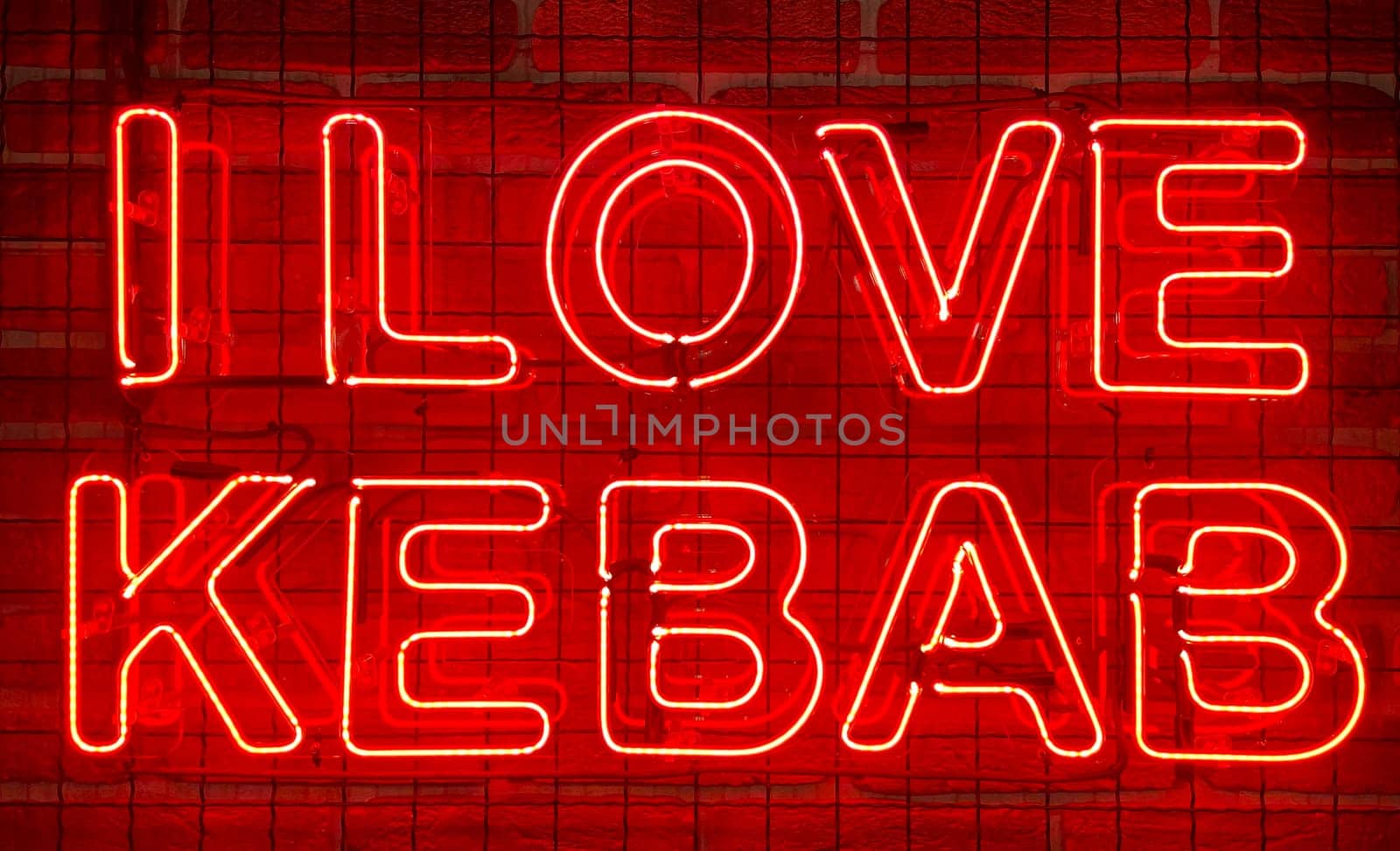 Neon shining sign in red color on a brick wall with the inscription or slogan I love kebab. Brick wall, background. Bright electric neon light. Cafe-restaurant Doner Kebab