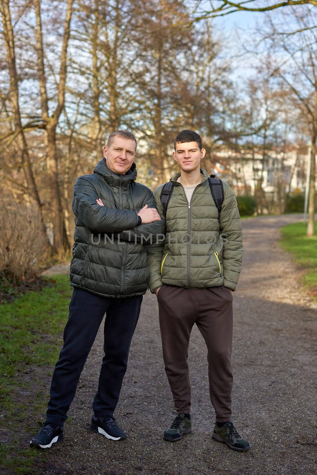 Father-Son Bond: Handsome 40-Year-Old Man and 17-Year-Old Son Standing Together in Winter or Autumn Park. by Andrii_Ko