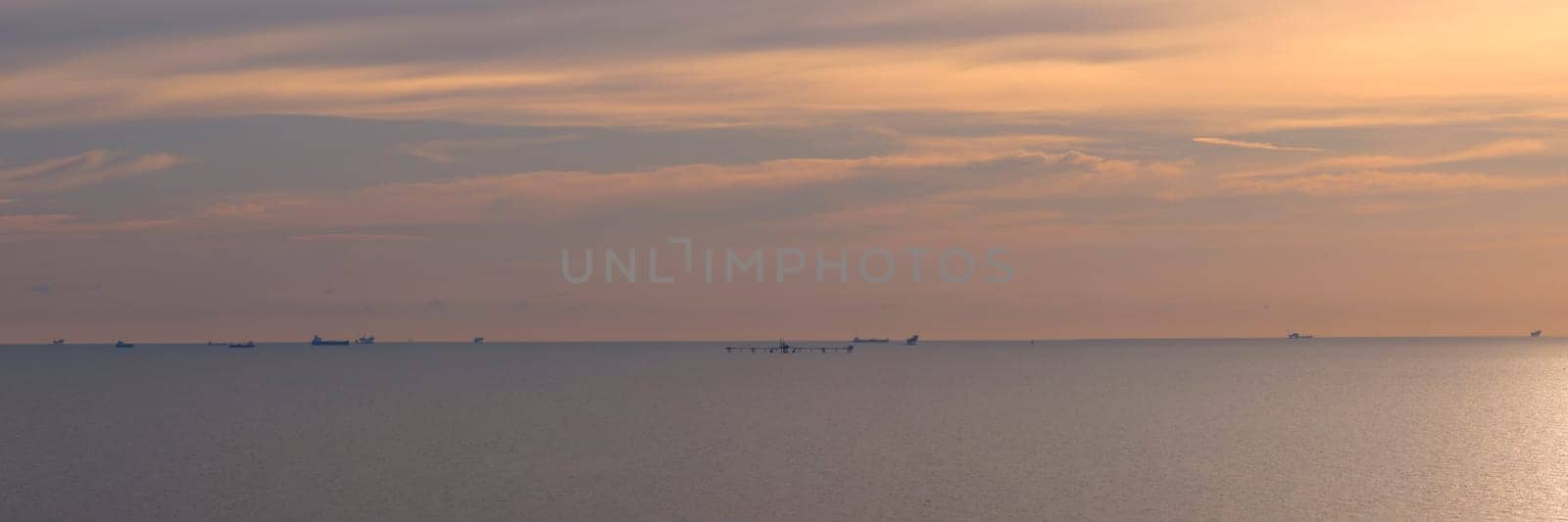 Panorama of dramatic sky at awesome sunset, flat sea at dawn, minimalist photo and mystery mood.