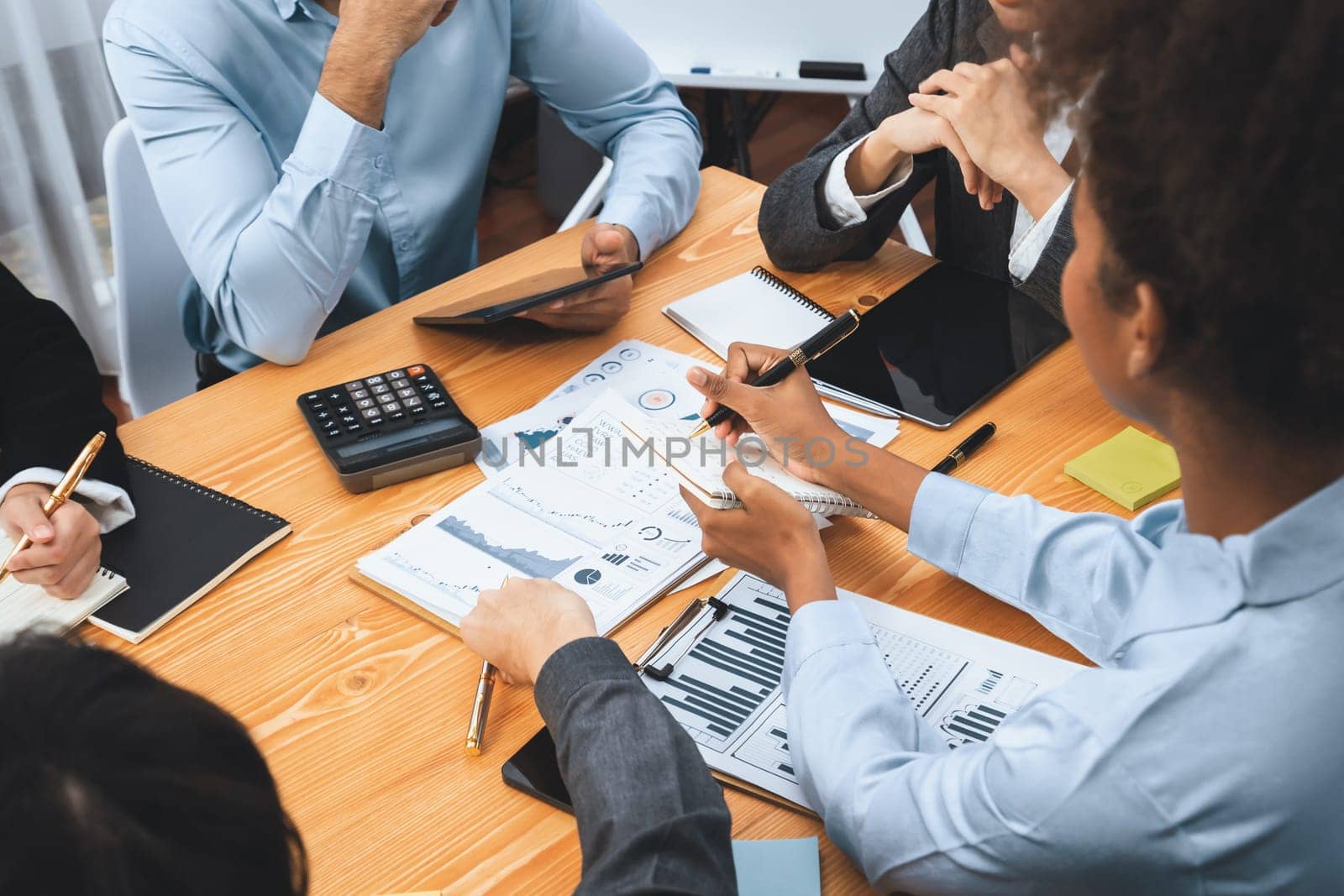 Multiracial analyst team use BI dashboard data to analyze financial report on meeting table. Group of diverse business people utilize data analysis by FIntech for business marketing decision. Concord