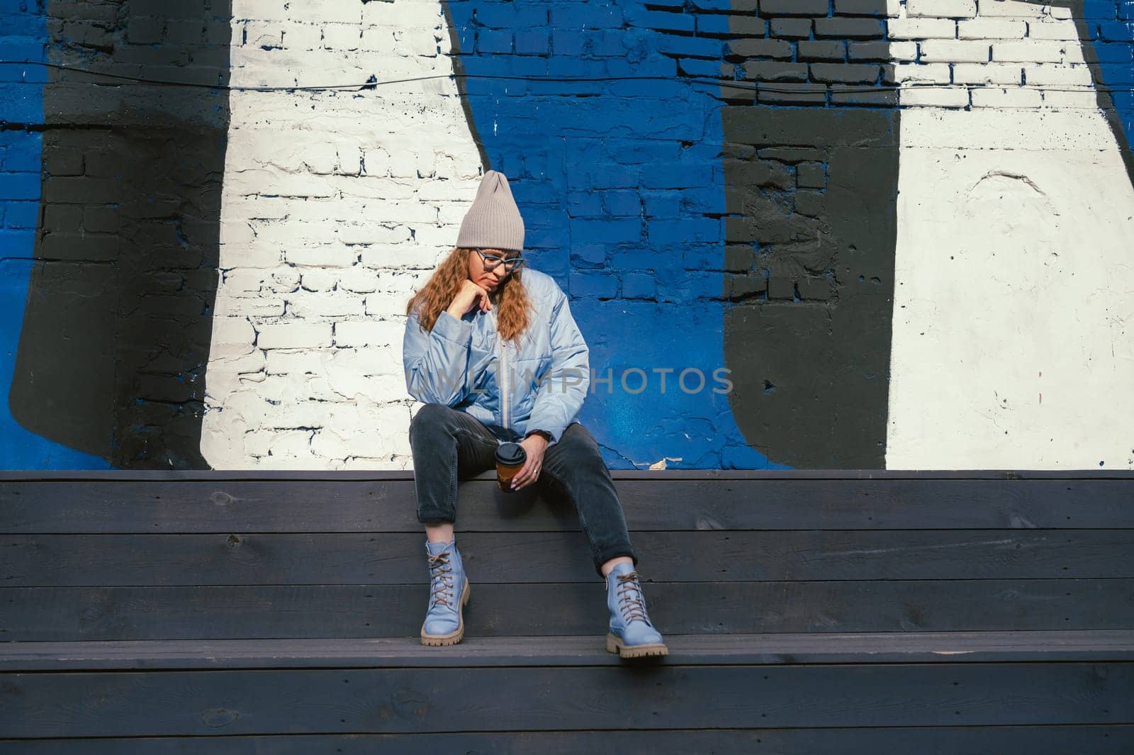 Portrait of a stylish woman in blue jacket with coffee cup. Spring outdoor portrait.