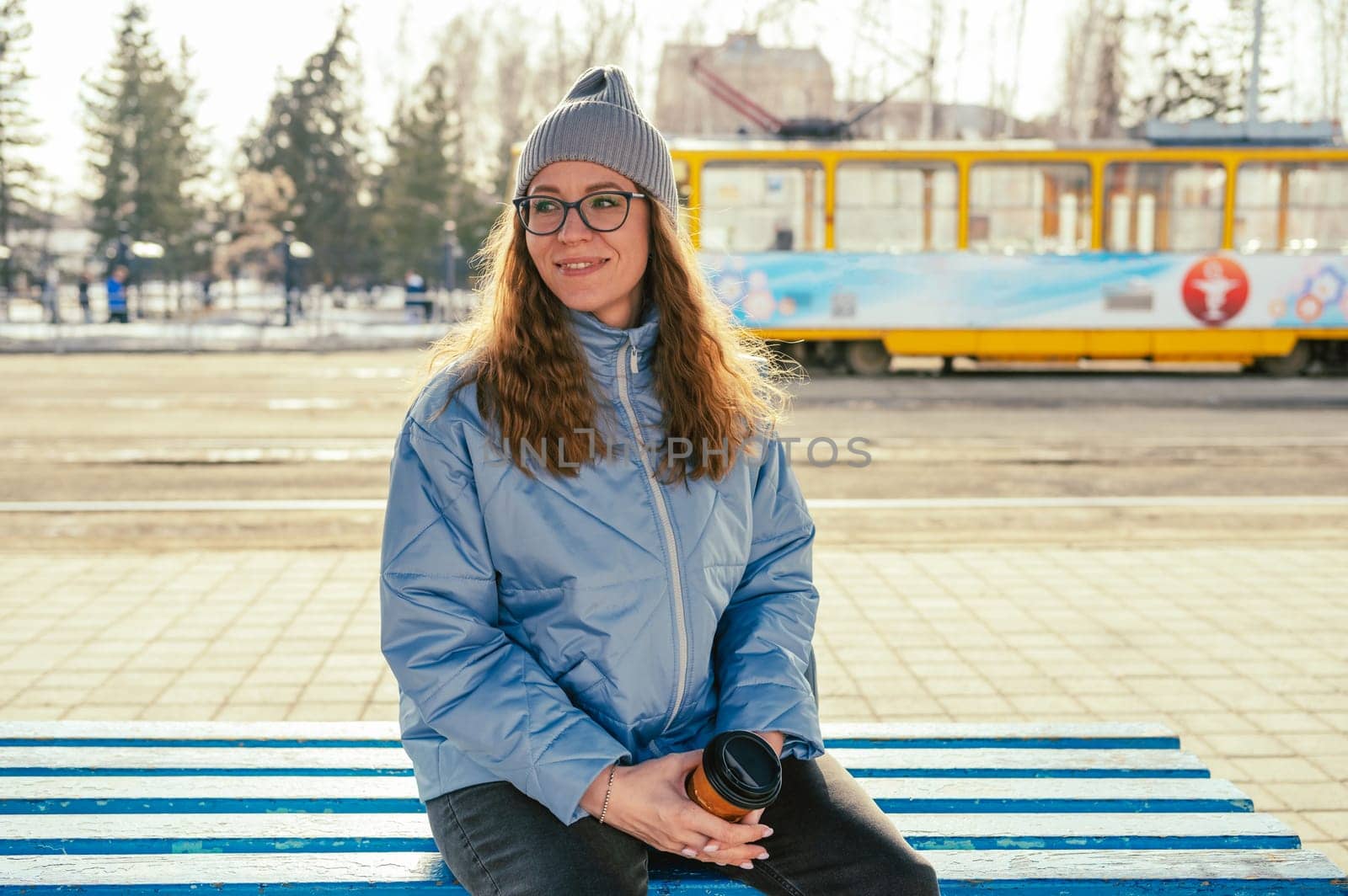 Portrait of a stylish woman in blue jacket with coffee cup. Spring outdoor portrait.