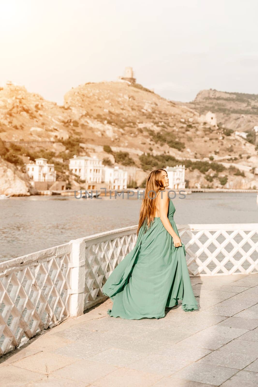 Woman sea trevel green dress. Side view a happy woman with long hair in a long mint dress posing on a beach with calm sea bokeh lights on sunny day. Girl on the nature on blue sky background