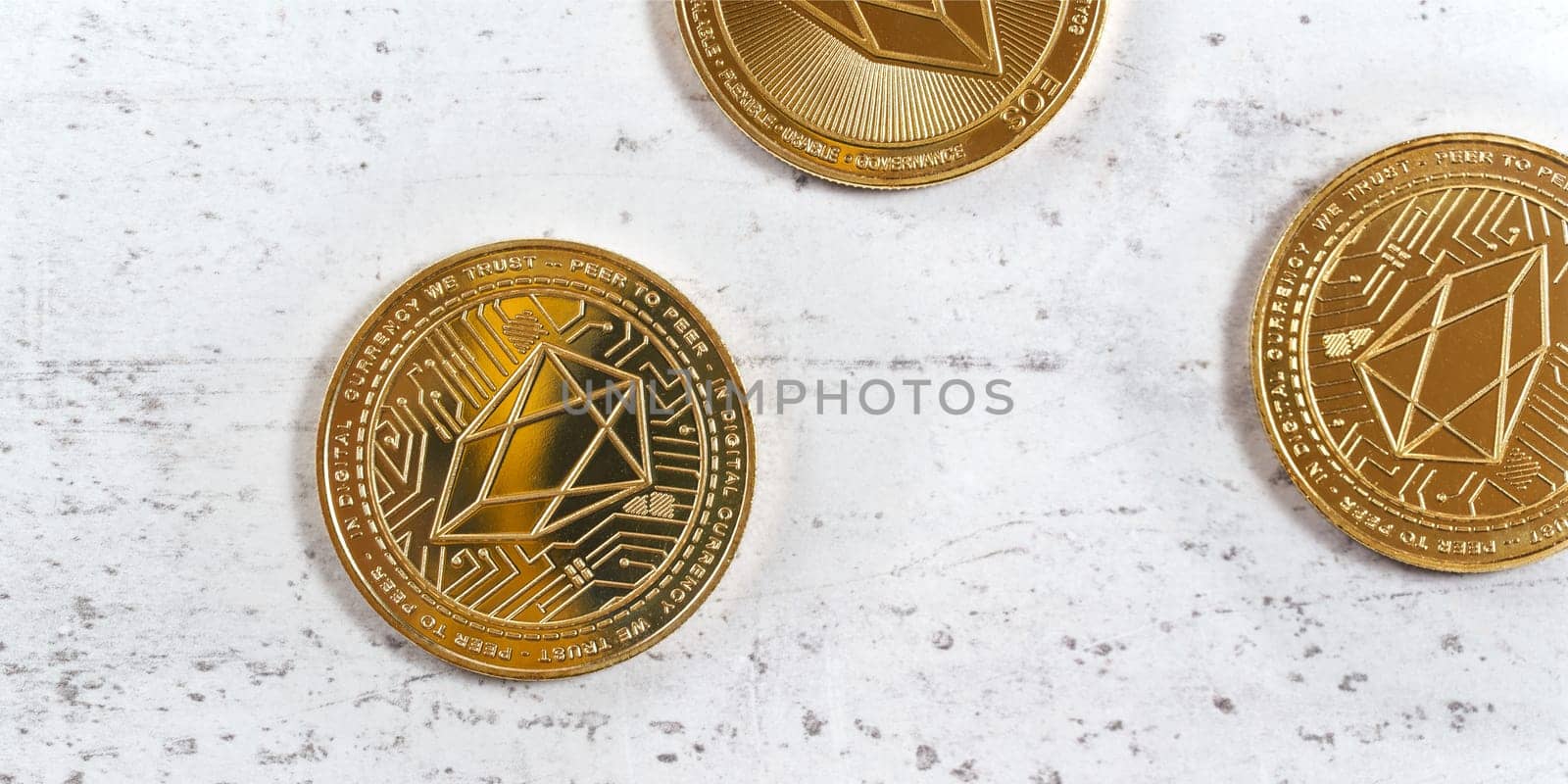 Top down view, golden commemorative EOS - EOSIO  cryptocurrency - coins on white stone board by Ivanko