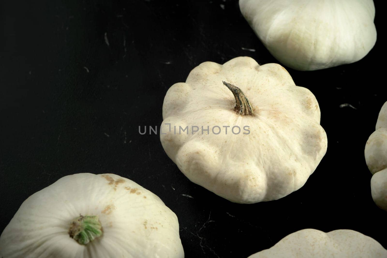 Closeup detail - group of white pattypan squash on black board by Ivanko