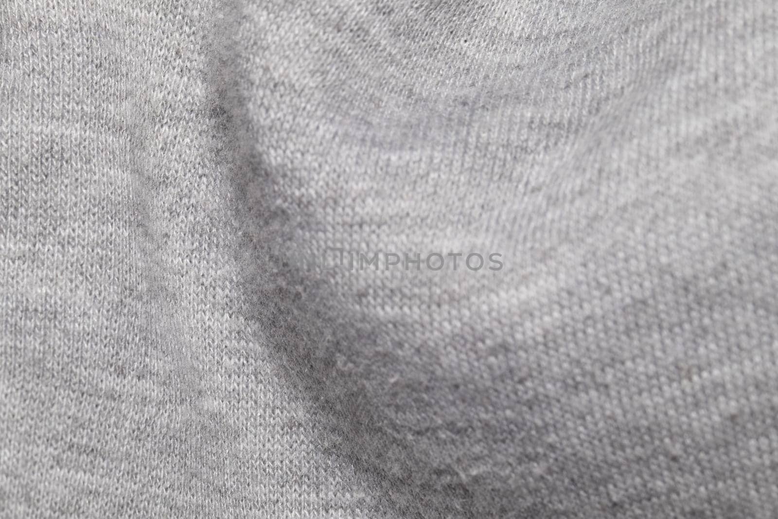 This image shows a close-up view of a gray knitted fabric, highlighting the intricate texture and weave pattern.