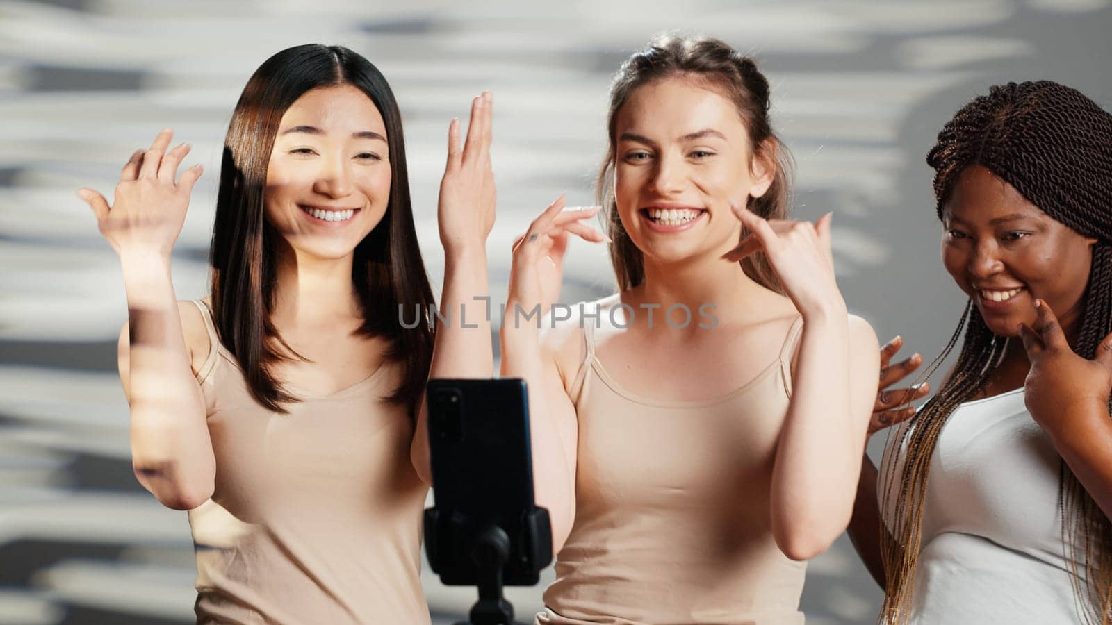 Silly beauty models dancing and having fun on camera, recording video with dance moves on smartphone and promoting self confidence. Happy beautiful women embracing imperfections.