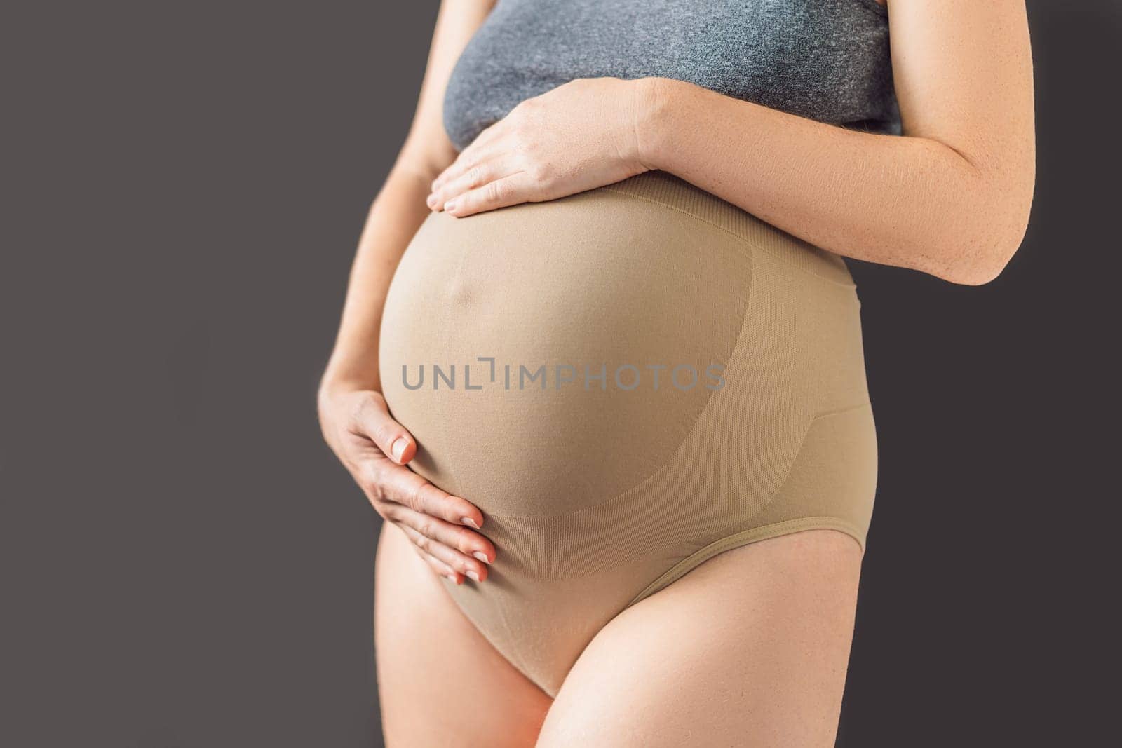Pregnant bliss: Mom-to-be embraces her baby bump with a soft fabric bandage, providing gentle support. Maternity made comfortable.