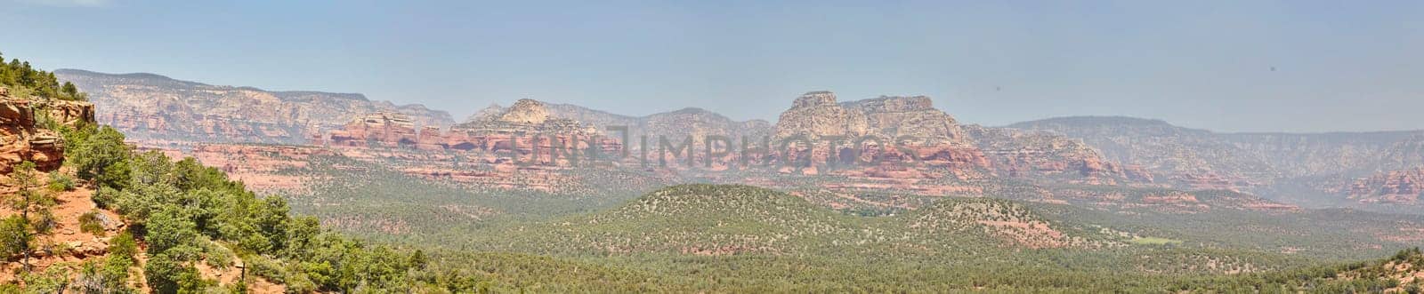 Panoramic view of Arizona's desert landscape featuring iconic red rock formations and sparse greenery under a clear blue sky in 2016, showcasing the tranquility and timeless beauty of Sedona.