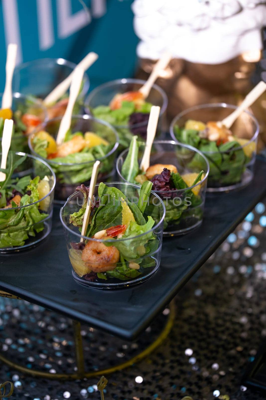 Fresh mixed salad with oranges, grilled shrimp, lettuce, and microgreens in a glass taster cup. Perfect for healthy eating, catering, or as a side dish. Isolated on a white background.