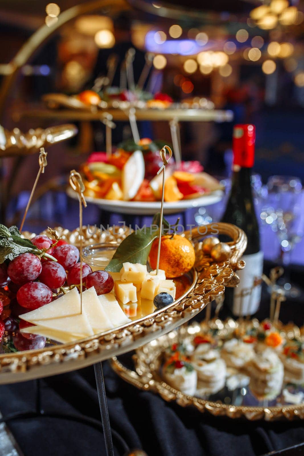 An assortment of fresh fruits, and cheeses are elegantly arranged on golden platters, creating a visually appealing and delicious display. Perfect for a party or any special occasion.