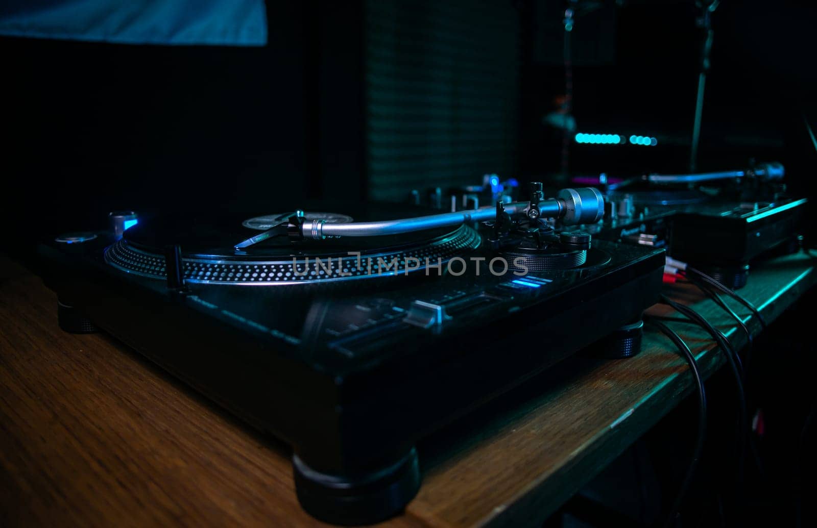 Black Turntable Playing Vinyl Record with Blue Light in the Background by Pukhovskiy