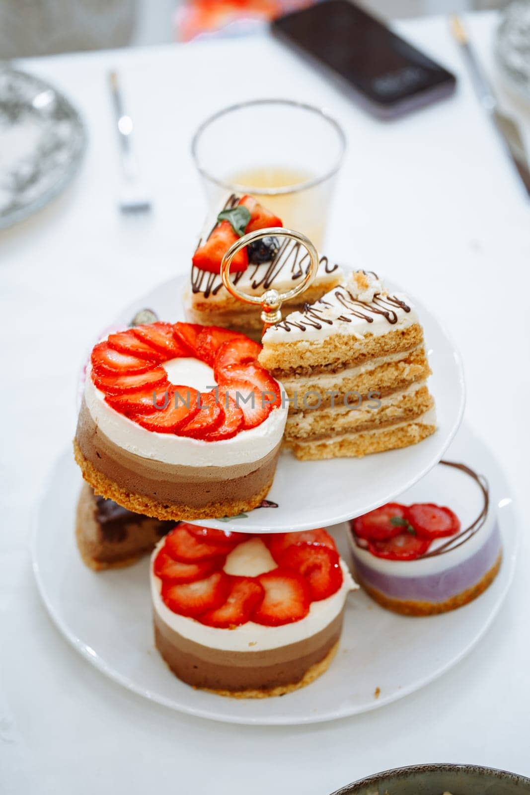 An elegant display of cakes and pastries on a three-tiered stand with a glass of orange juice. The image exudes indulgence and sophistication, perfect for a high-end bakery or cafe.