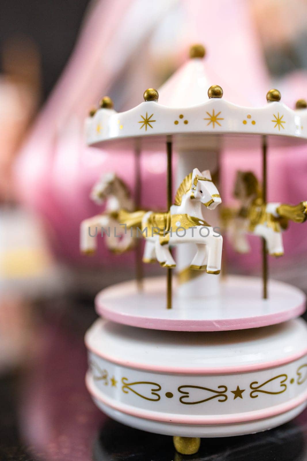 White and pink music carousel with gold horses on dark background by Pukhovskiy