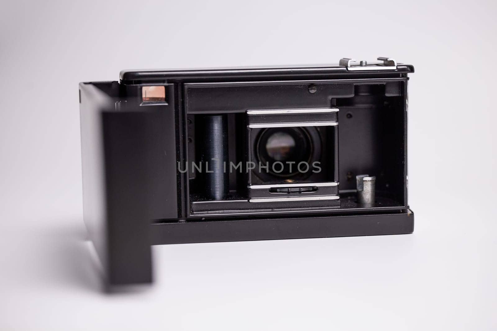 Black and silver retro camera with the back open and film exposed on a white background by Pukhovskiy