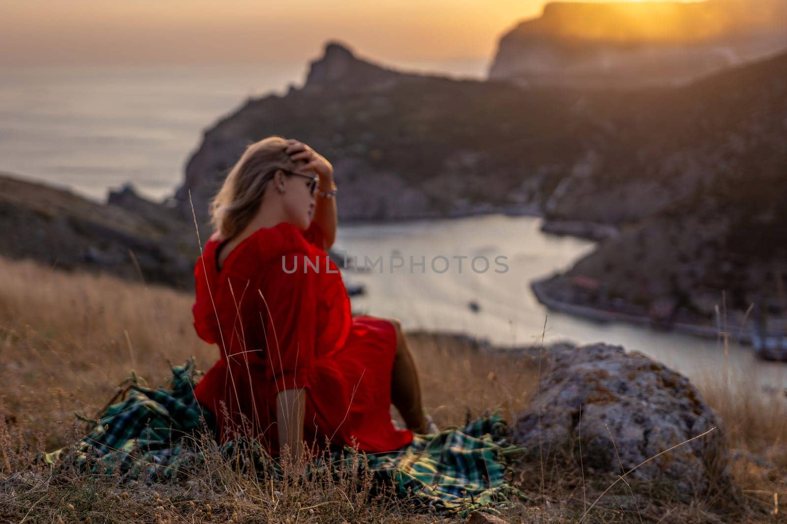 Woman sunset sea mountains. Happy woman siting with her back on the sunset in nature summer posing with mountains on sunset, silhouette. Woman in the mountains red dress, eco friendly, summer landscape active rest by Matiunina