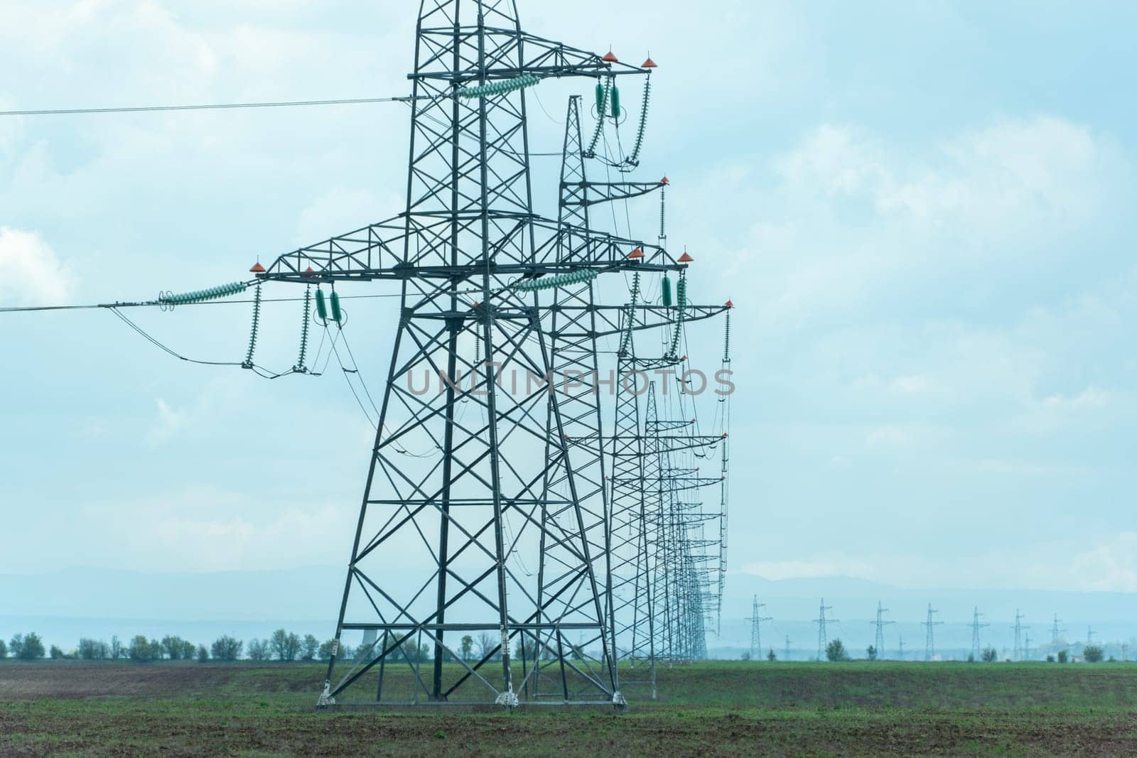 High voltage towers with sky background. Power line support with wires for electricity transmission. High voltage grid tower with wire cable at distribution station. Energy industry, energy saving.