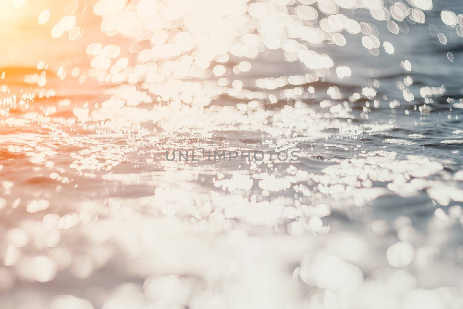 Abstract sea summer ocean sunset nature background. Small waves on golden water surface in motion blur with golden bokeh lights from sun. Holiday, vacation and recreational concept. by panophotograph