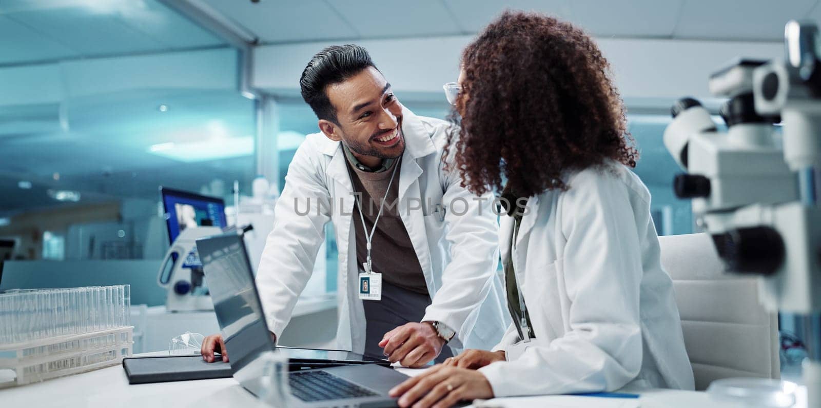 Scientist, teamwork and happy with laptop in laboratory for test breakthrough, pharmaceutical review or success. Science, collaboration or technology for research, discussion and digital analysis.