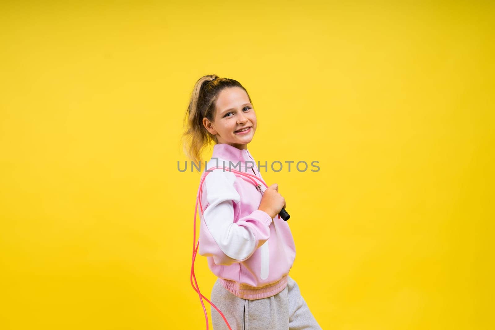Beautiful sportsgirl with skipping rope isolated on a yellow studio