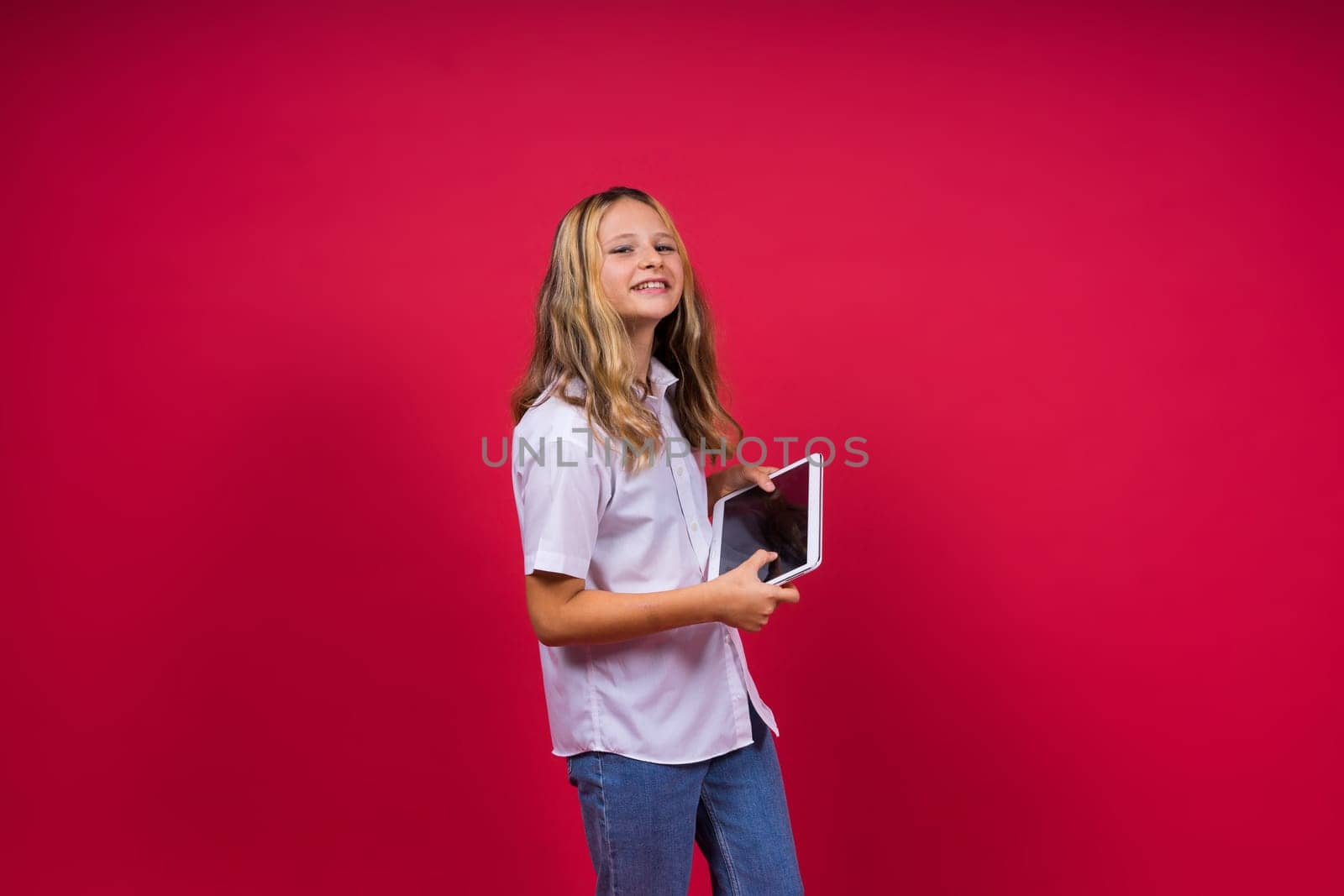 Online school app. Schoolgirl showing tablet computer Empty Screen On red Background. Studio Shot